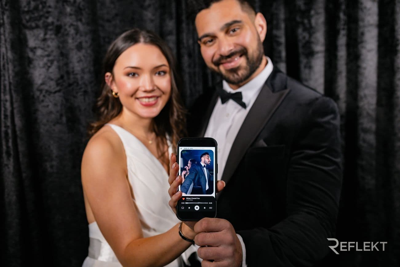 Couple showing the video they just received from the booth on a phone