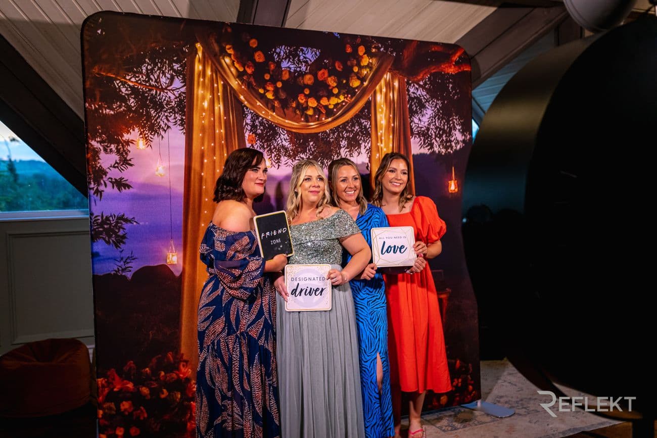 Group of guests posing with signs in front of a themed photo booth backdrop
