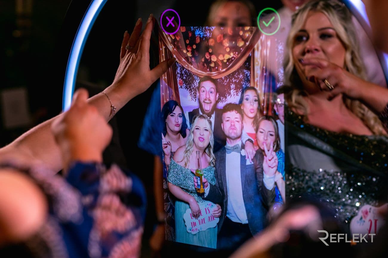 Guests choosing a photo on the touchscreen of a round beauty mirror photo booth