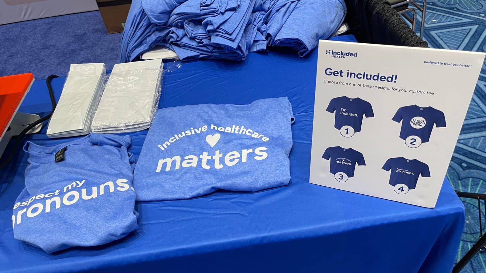 Custom-pressed shirts and a numbered design menu at a live heat press station