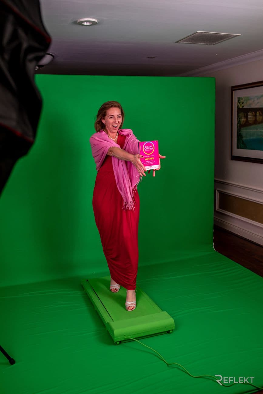 Guest posing on a green screen photo booth set
