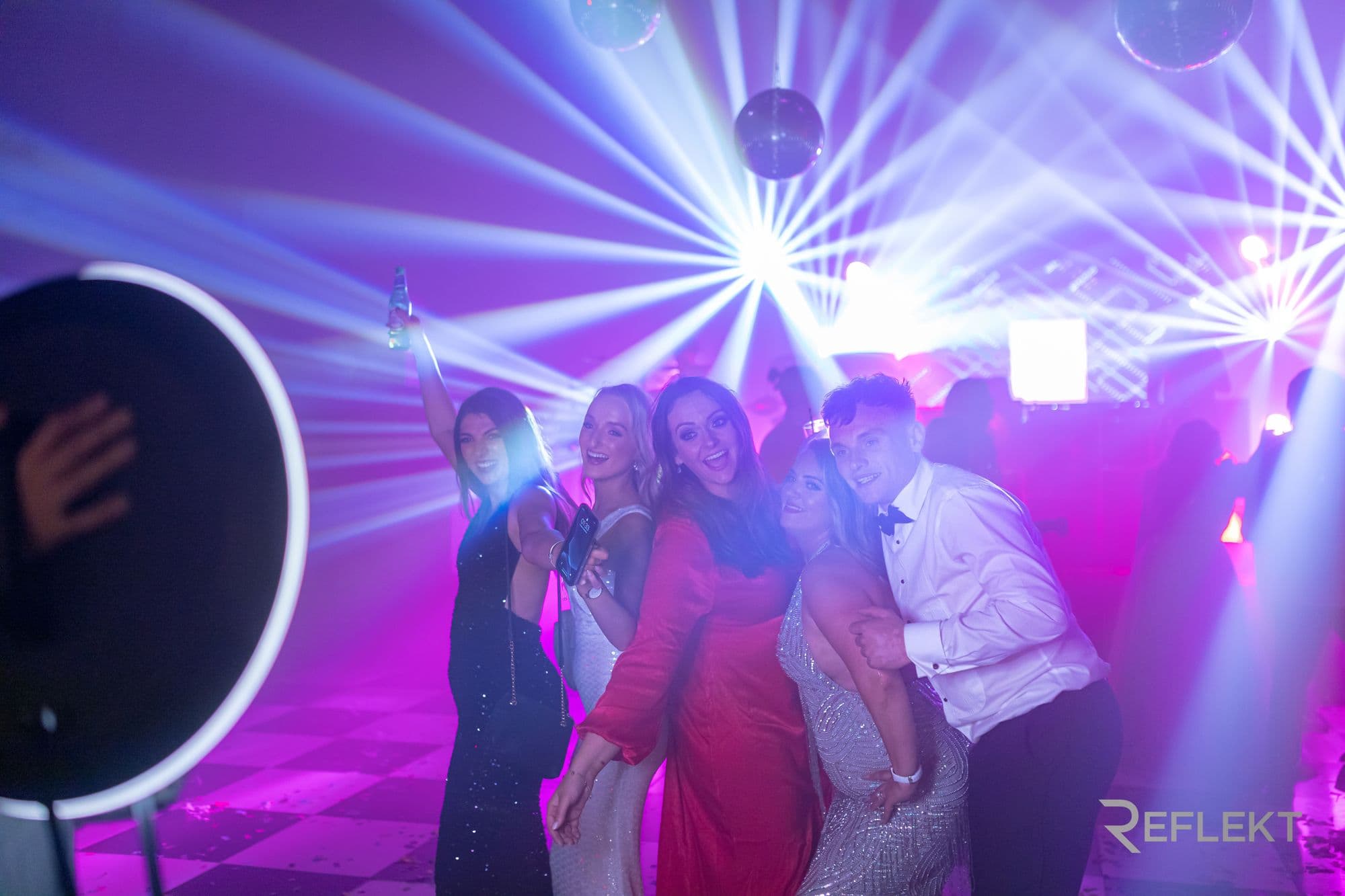 Guests enjoying a Reflekt photo booth at an evening celebration