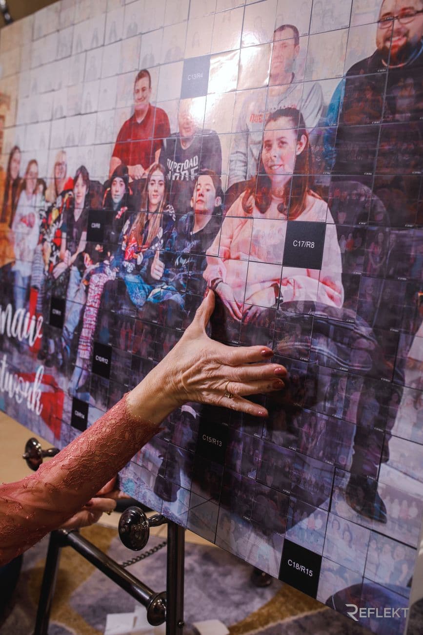 Guest adding a print to a photo mosaic wall at a corporate event