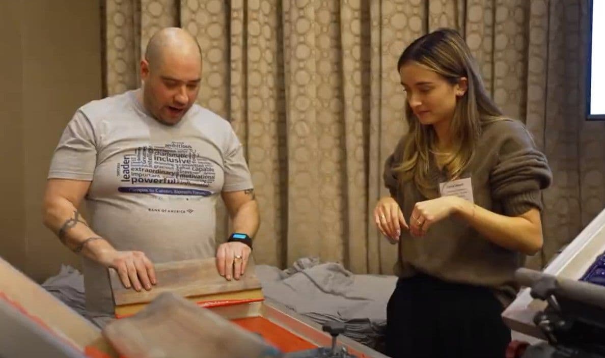 Printer pulling a live screen print while a guest watches at a corporate event